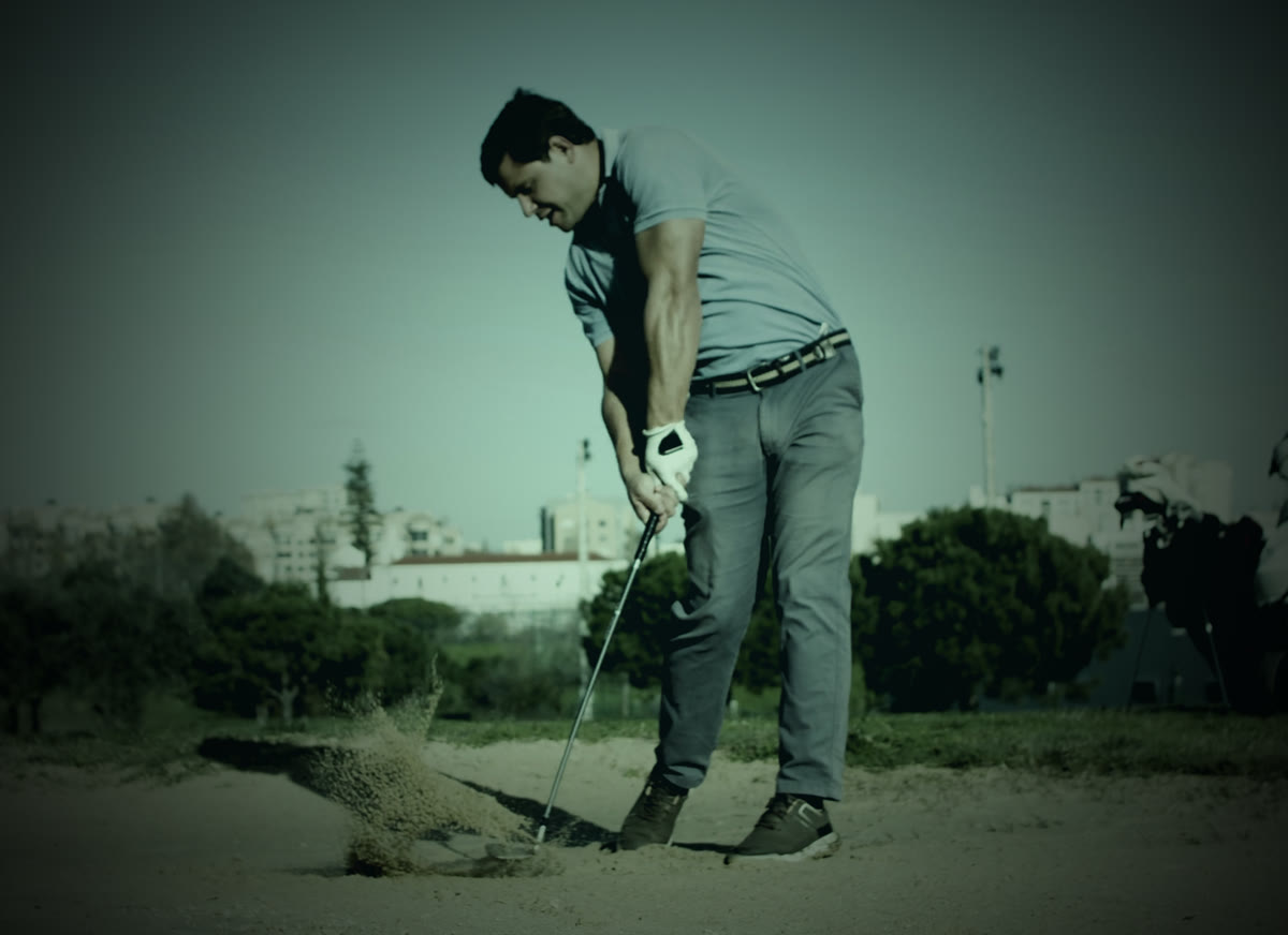 Golfista no momento do impacto, com areia levantando